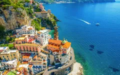 Küstenstadt mit bunten Häusern und Kirche am Meer.