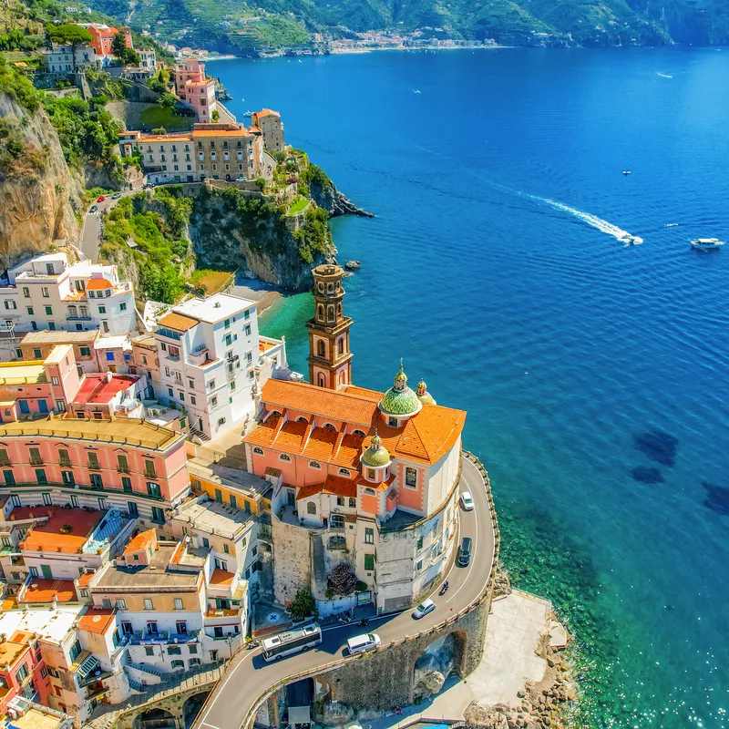 Küstenstadt mit bunten Häusern und Kirche am Meer.