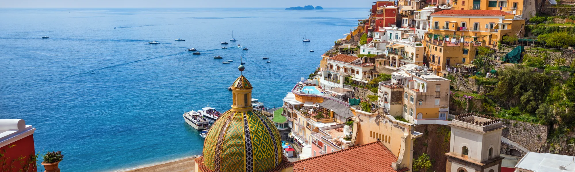 Küstenstadt mit bunten Häusern und blauem Meer im Hintergrund.