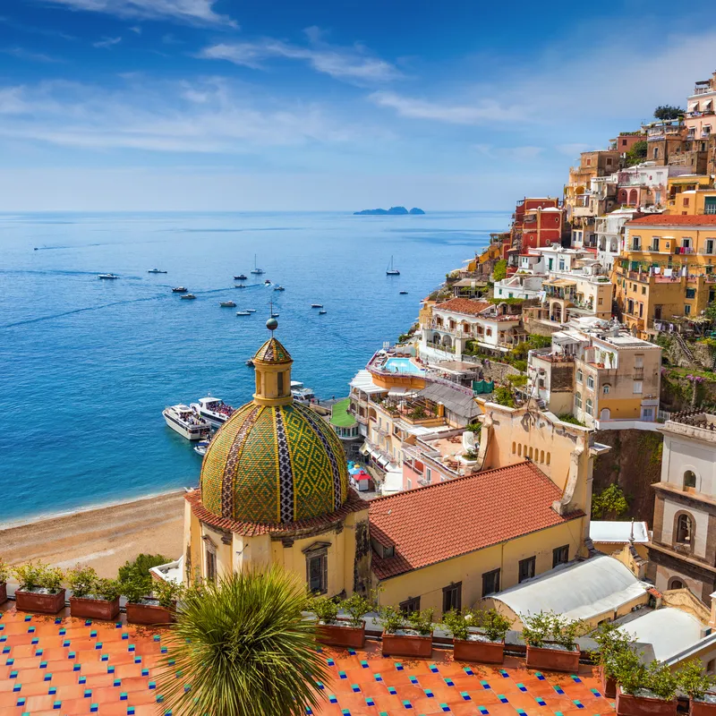 Küstenstadt mit bunten Häusern und blauem Meer im Hintergrund.