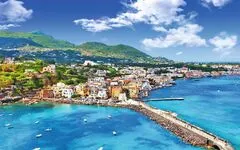 Blick auf eine mediterrane Küstenstadt mit bunten Häusern und klarem blauen Wasser.