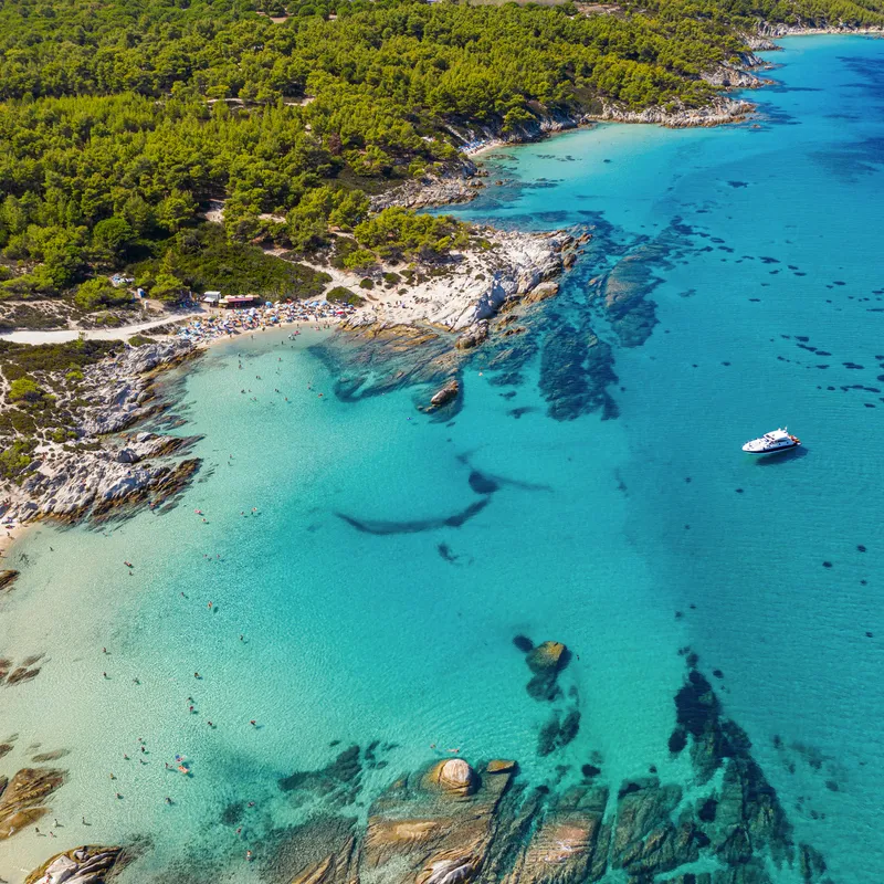Luftaufnahme einer Küste mit klarem Wasser und einem Boot.