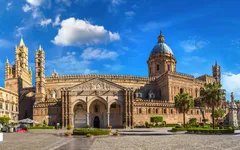 Kathedrale von Palermo an einem sonnigen Tag, umgeben von Palmen und historischer Architektur.