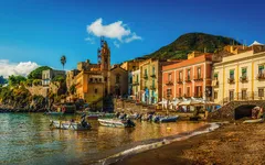Hafenstadt mit bunten Häusern und Booten am Strand, Liparische Inseln, Italien.