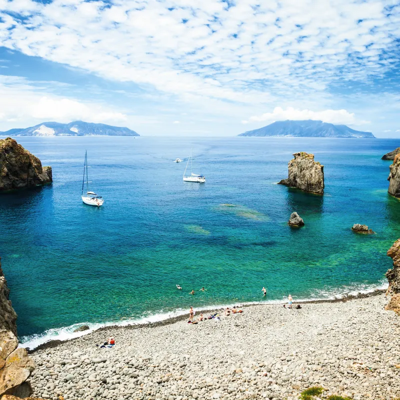 Strandbuch mit klarem Wasser und Booten auf der Insel Panarea, Liparische Inseln, Italien.