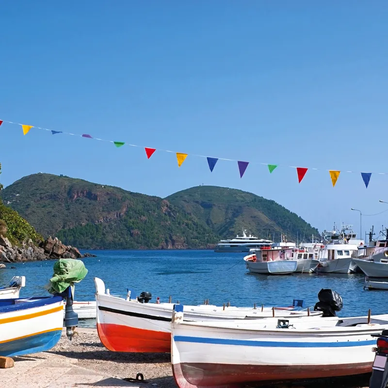 Boote im Hafen der liparischen Inseln, Italien, mit bunten Wimpeln über dem Wasser.