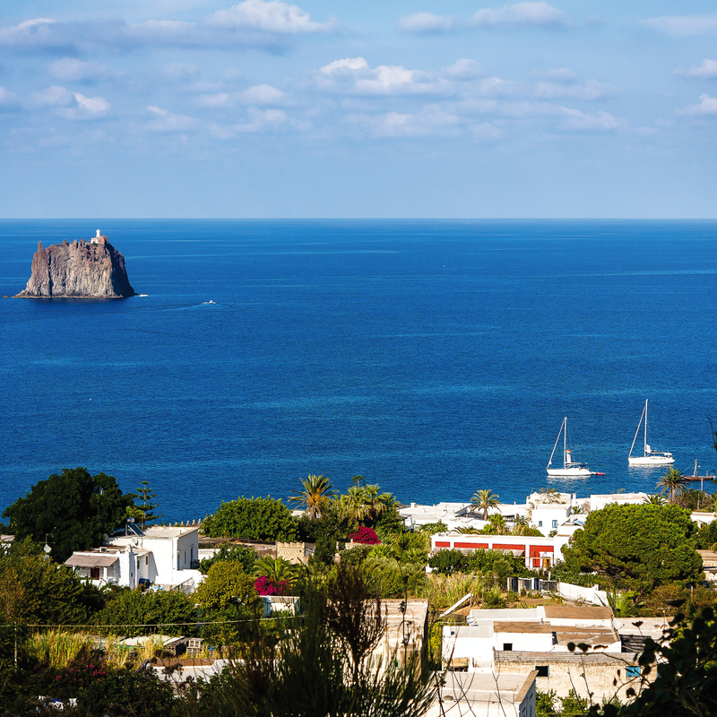 Blick auf Stromboli und Meer mit Segelbooten auf den Liparischen Inseln in Italien.