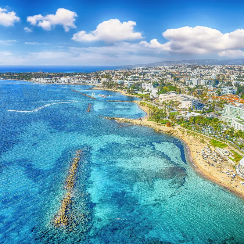 Luftaufnahme einer Küstenstadt mit klarem, blauem Wasser und Sandstränden.