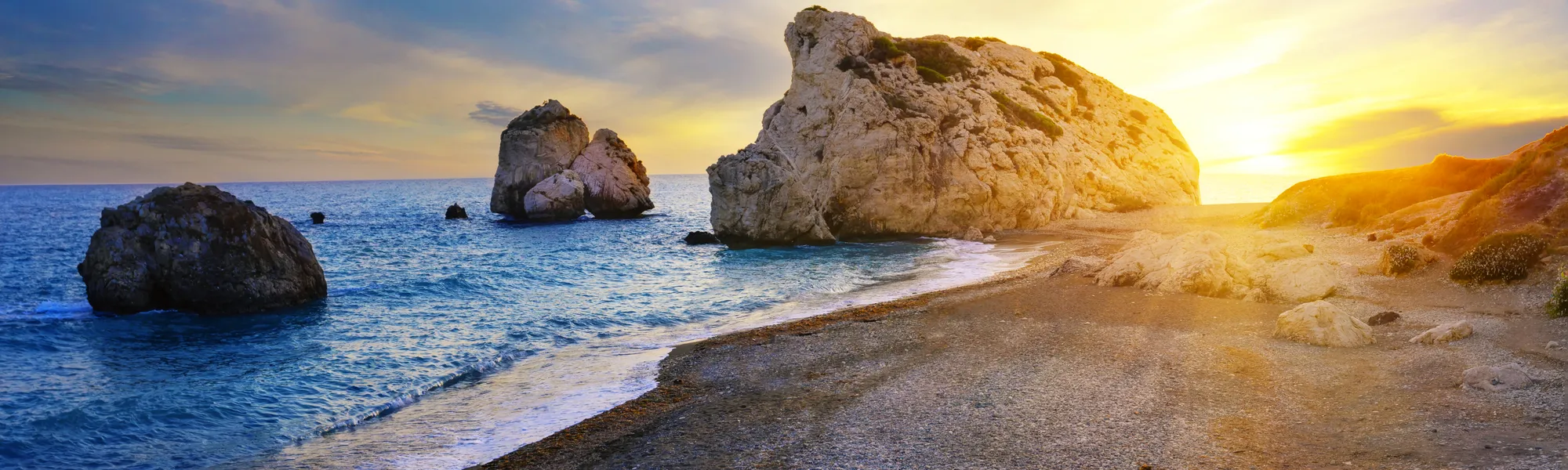 Strand mit Felsen und Sonnenuntergang am Meer.