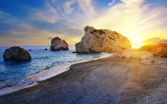 Strand mit Felsen und Sonnenuntergang am Meer.