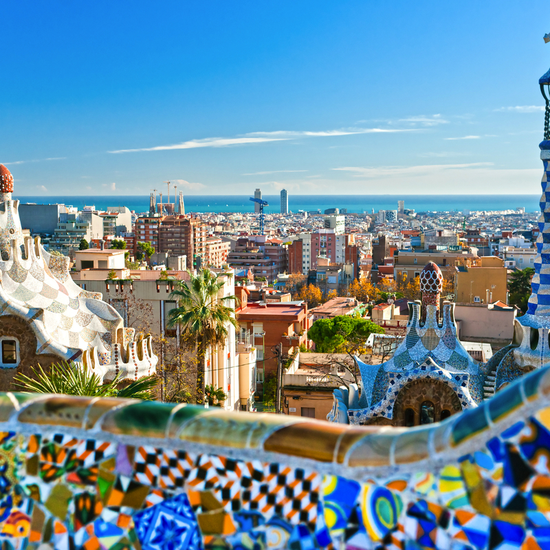 Blick auf die Stadt Barcelona mit Gaudí-Architektur im Vordergrund und dem Meer im Hintergrund.