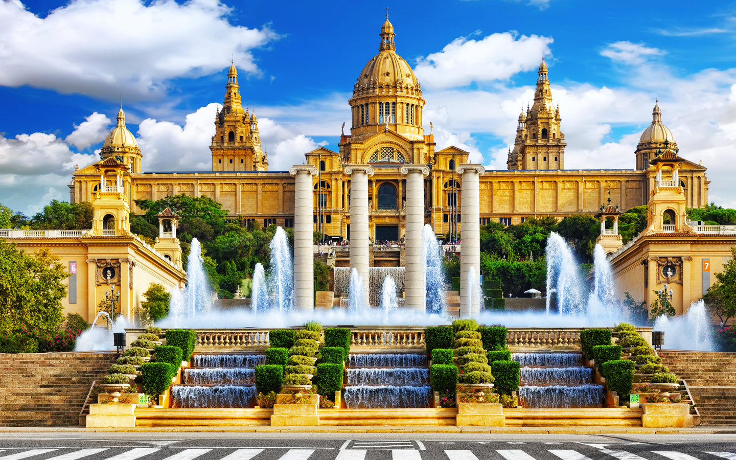 Historisches Gebäude mit Brunnen und Treppen vor blauem Himmel.