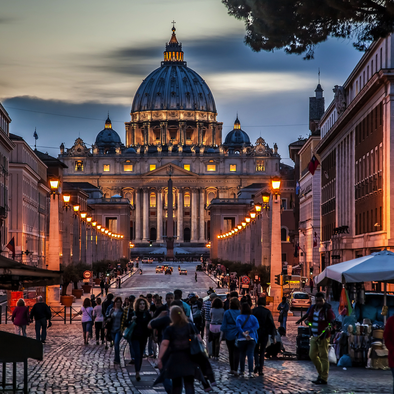 Nachtansicht der beleuchteten Basilika St. Peter in Rom auf dem Petersplatz bei Dämmerung.