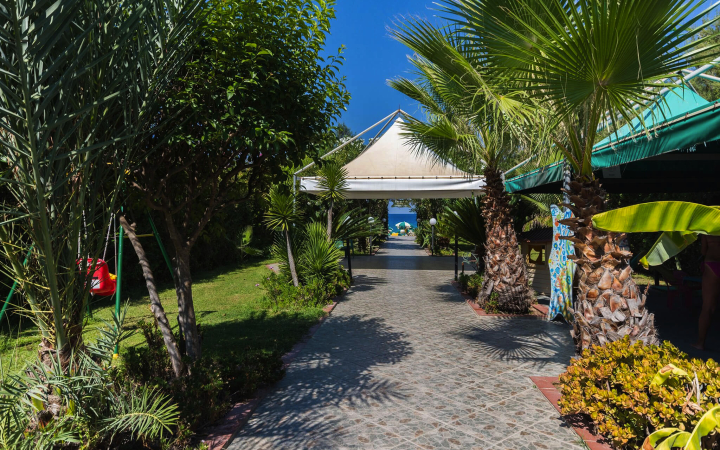 Gartenweg mit Palmen im Hotel La Praia, Kalabrien, Italien.