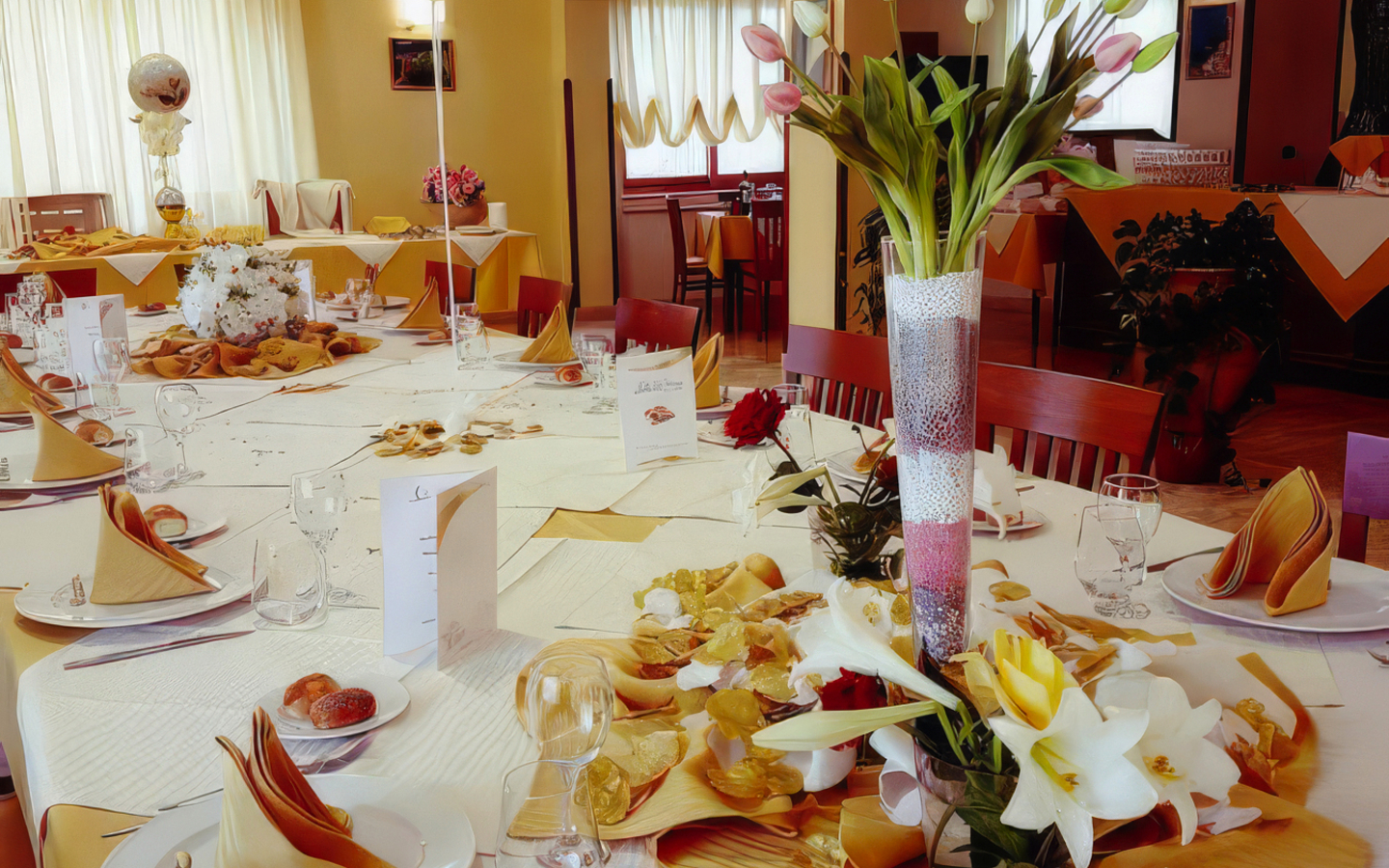 Festlicher Tisch in einem Restaurant mit Blumen und gedecktem Geschirr.