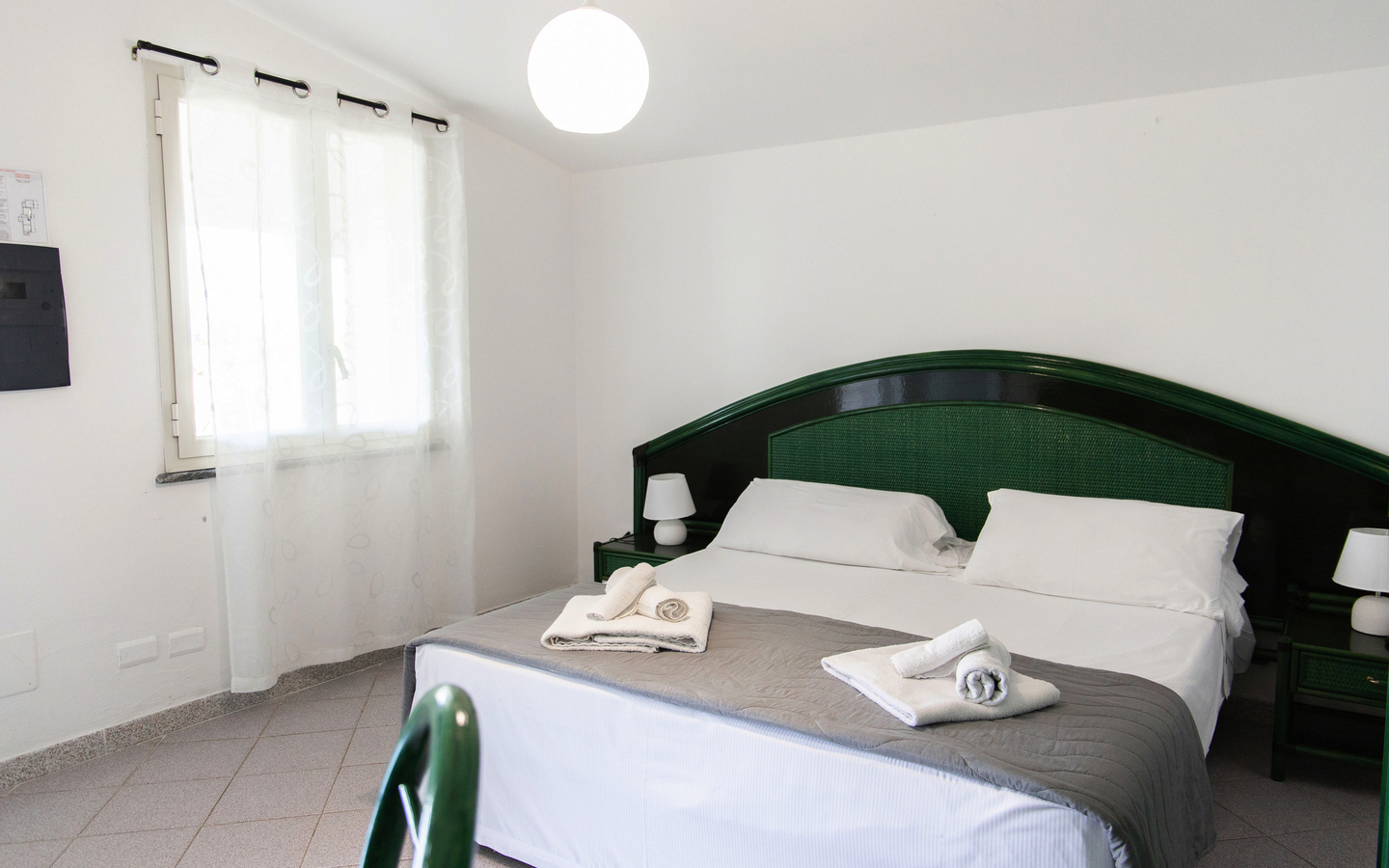 Helles Hotelzimmer mit Doppelbett, zwei Nachttischen und einem Fenster.