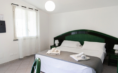 Helles Hotelzimmer mit Doppelbett, zwei Nachttischen und einem Fenster.