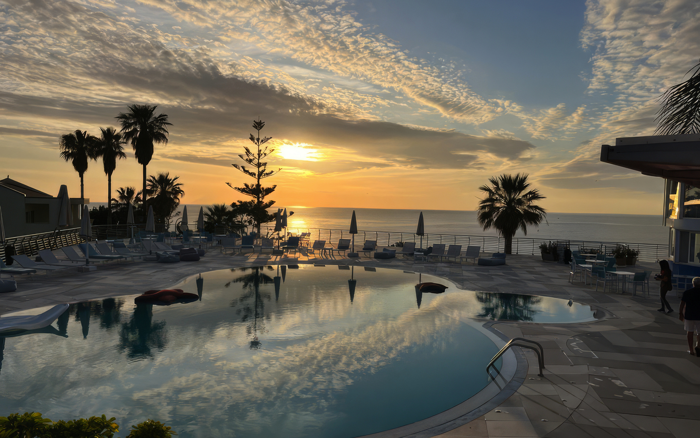 Hotelpool bei Sonnenuntergang mit Palmen und Meerblick in Kalabrien, Italien.