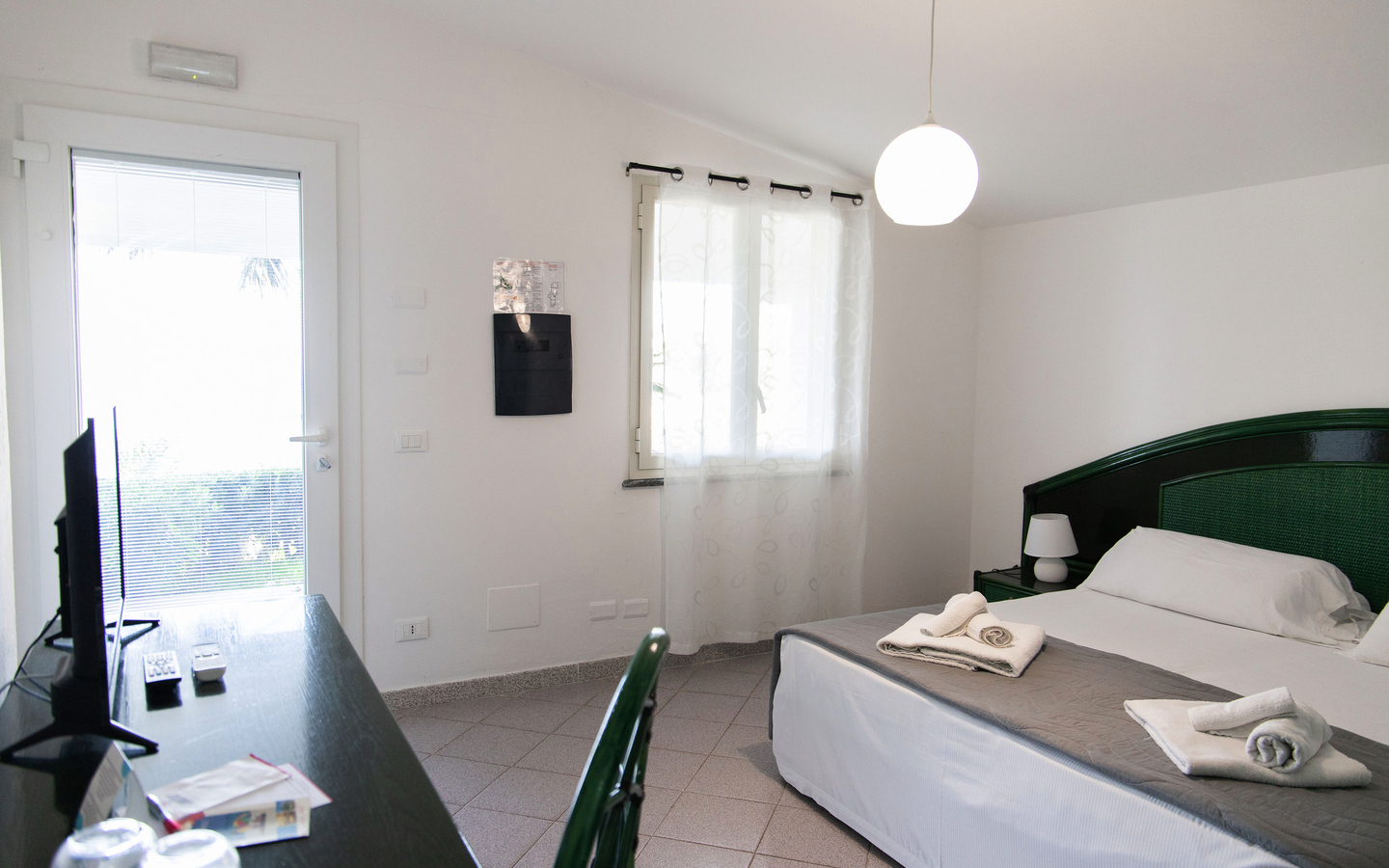 Standardzimmer mit Doppelbett, Schreibtisch, TV und heller Einrichtung.