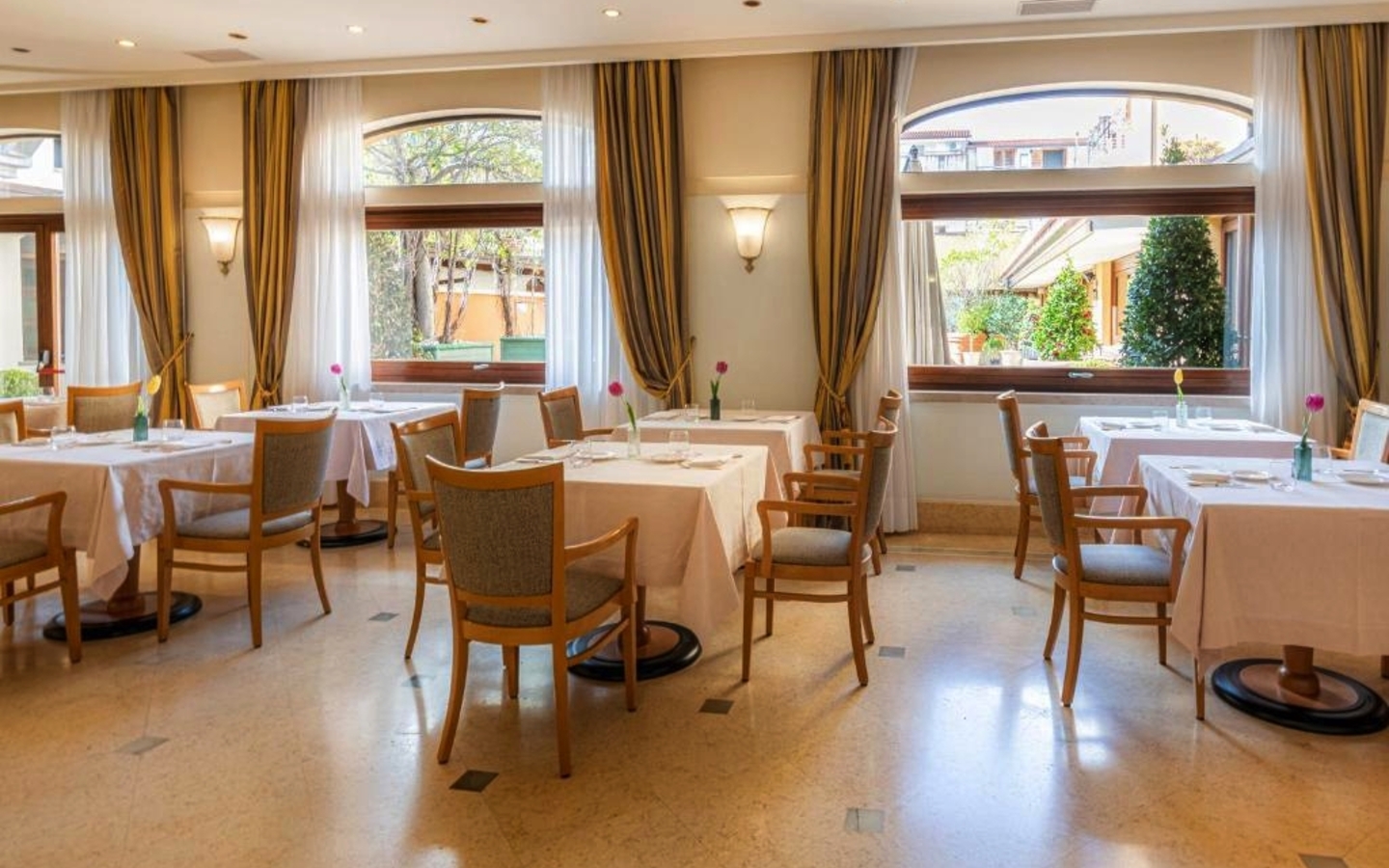 Helles Restaurant mit gedeckten Tischen und großen Fenstern im Hotel Cala del Porto.