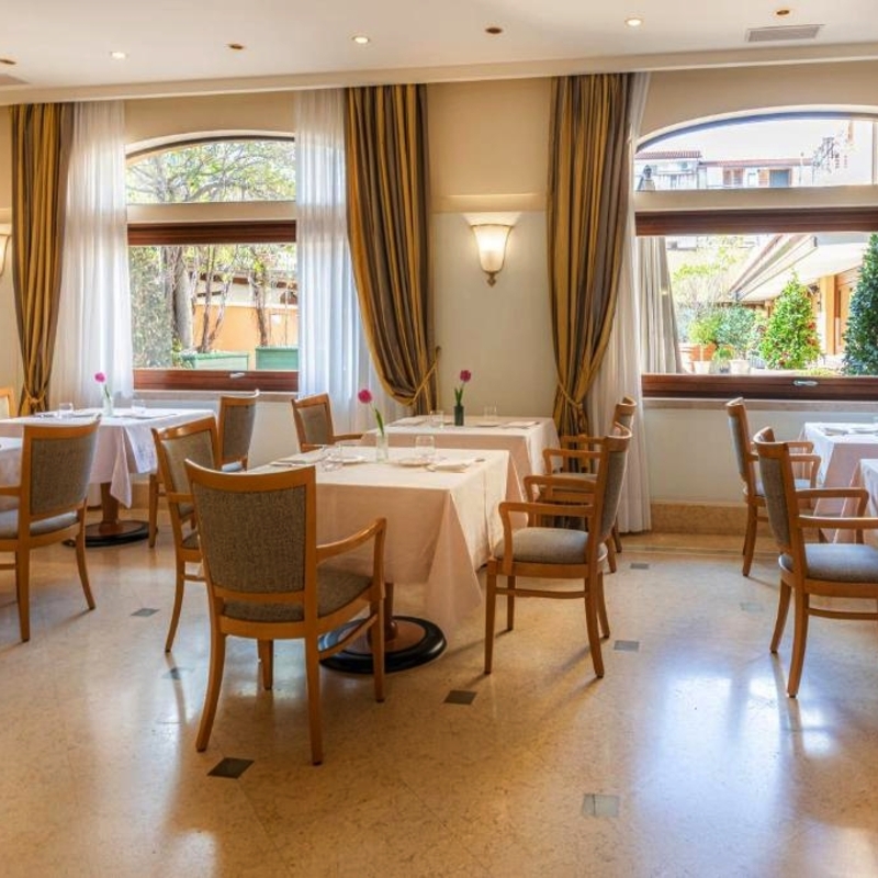 Helles Restaurant mit gedeckten Tischen und großen Fenstern im Hotel Cala del Porto.