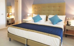 Doppelzimmer mit Bett, Nachttischen und Lampe in neutralen Farben.