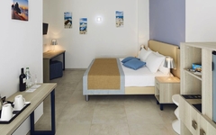 Helles Hotelzimmer mit Doppelbett, Schreibtisch, Kunst an den Wänden und moderner Einrichtung.