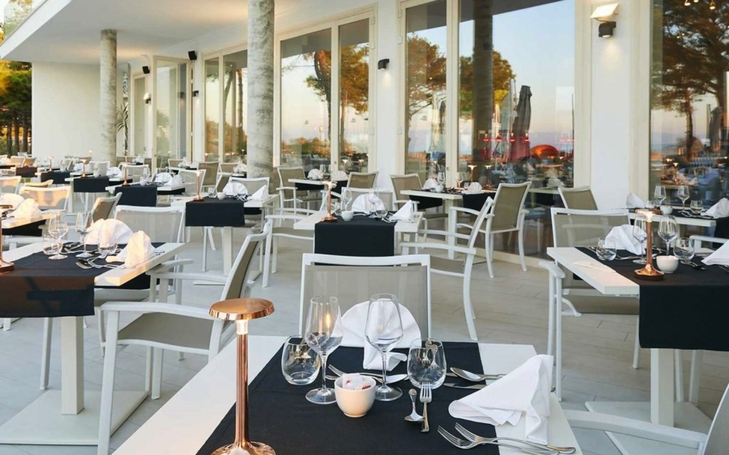 Restaurant im Freien mit gedeckten Tischen und Blick auf die Terrasse in der Abenddämmerung.