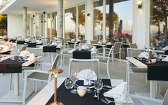 Restaurant im Freien mit gedeckten Tischen und Blick auf die Terrasse in der Abenddämmerung.