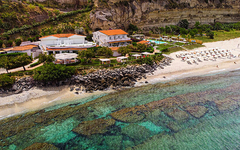 Luftaufnahme des Borgo di Riaci Resorts in Kalabrien mit Strand und klarem Wasser.