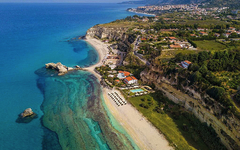 Luftaufnahme von Strand und Küste in Kalabrien, Italien, mit Resort und Klippen.