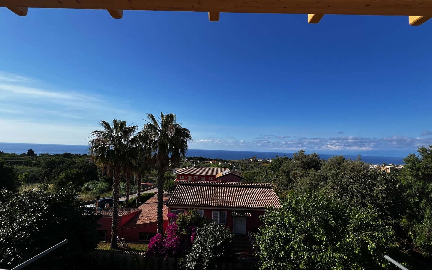 Aussicht auf Hotel in Kalabrien mit Palmen und Meer im Hintergrund.