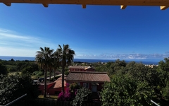 Aussicht auf Hotel in Kalabrien mit Palmen und Meer im Hintergrund.