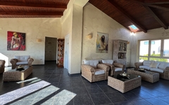 Sitzbereich mit Rattanmöbeln in heller Lounge, große Fenster, Holzdach.