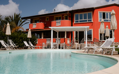 Hotel mit Pool in Kalabrien, Italien, umgeben von Liegestühlen und Sonnenschirmen.