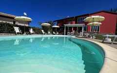 Außenansicht eines Pools mit Liegestühlen und Sonnenschirmen im Hotel Borgo di Santa Barbara.