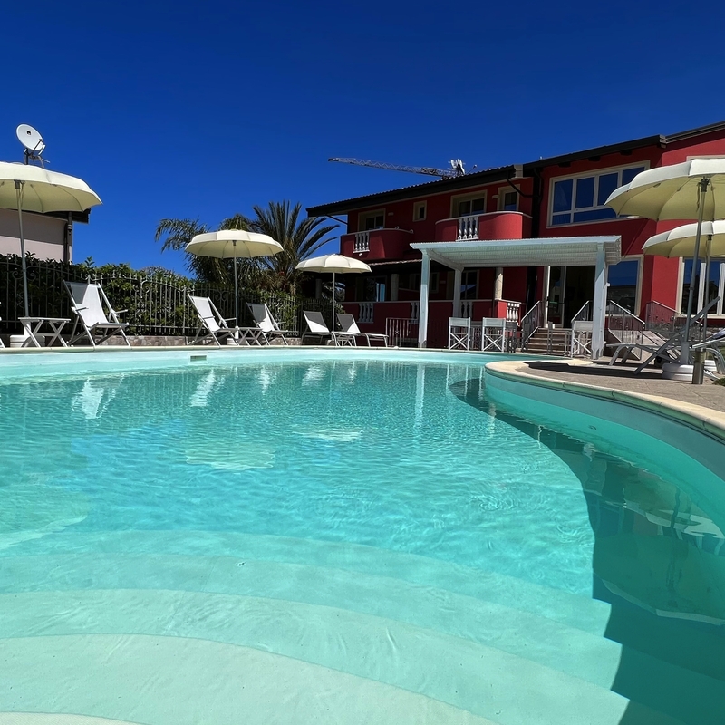 Außenansicht eines Pools mit Liegestühlen und Sonnenschirmen im Hotel Borgo di Santa Barbara.