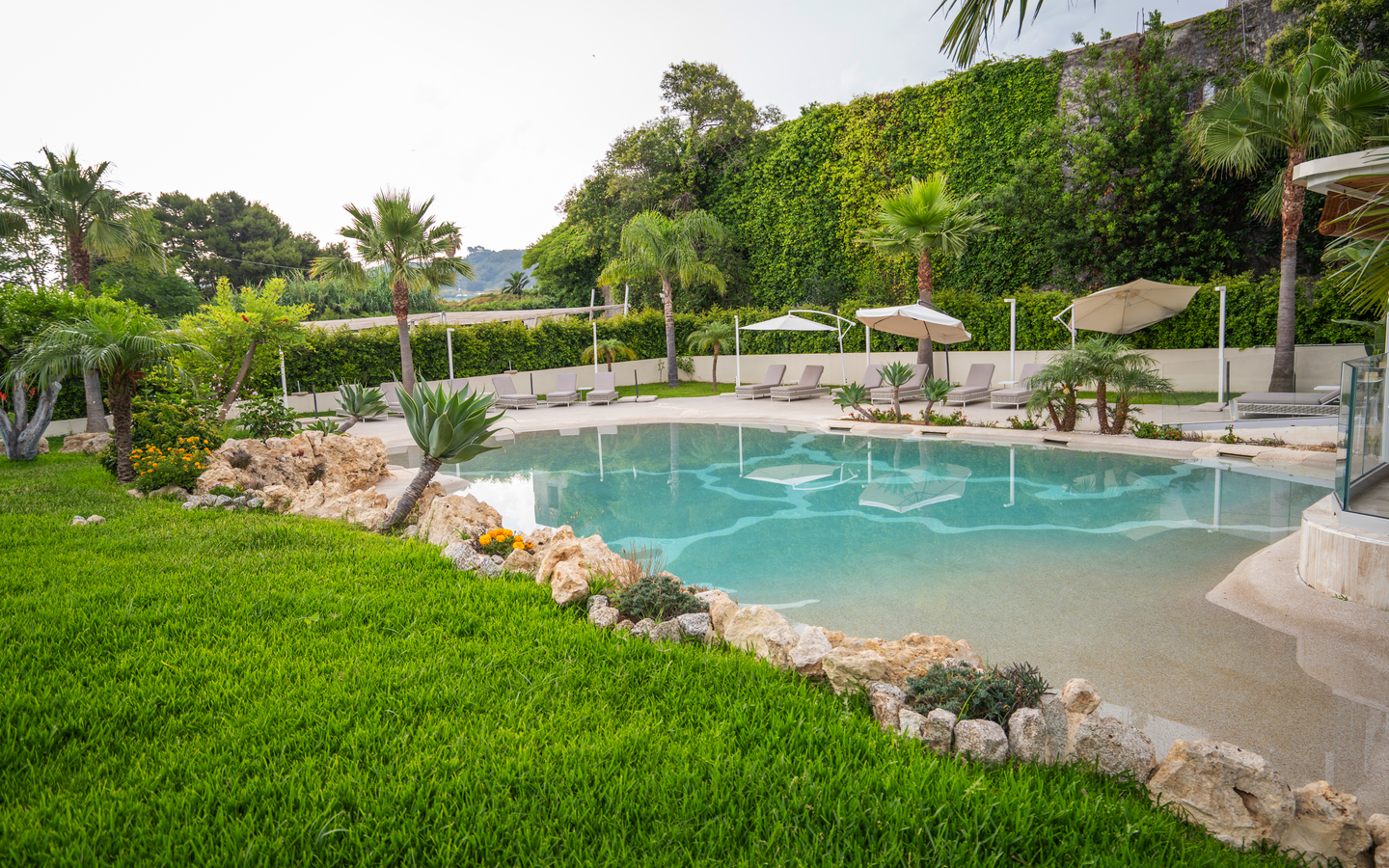 Poolbereich mit Liegestühlen und Palmen in einem Hotel in Kalabrien, Italien.