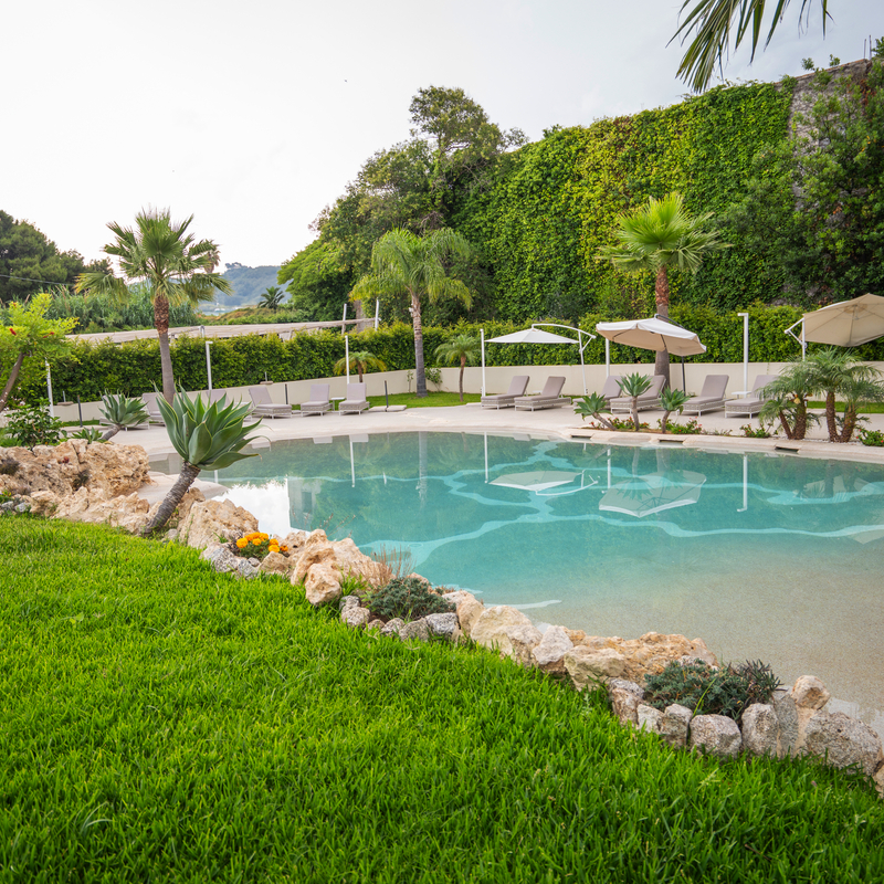 Poolbereich mit Liegestühlen und Palmen in einem Hotel in Kalabrien, Italien.