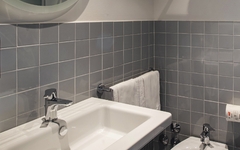 Badezimmer mit Waschbecken, Spiegel und grauen Kacheln im Hotel Ibis Styles Roma Aurelia.