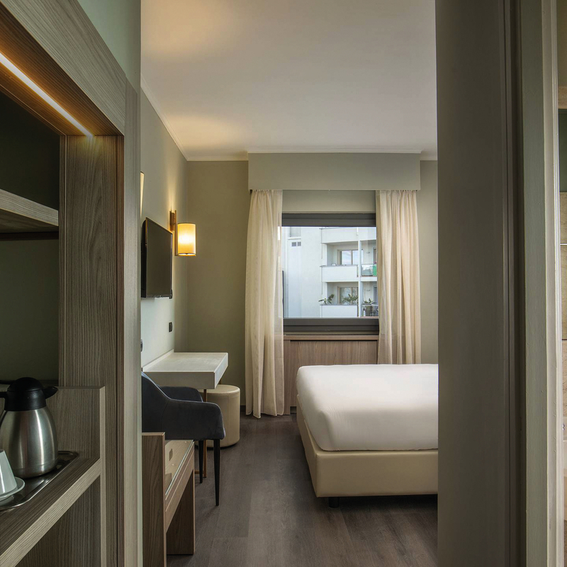 Hotelzimmer mit Doppelbett, Schreibtisch, Sessel und ein helles Badezimmer.