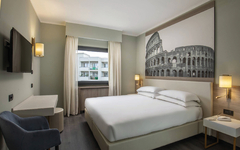 Modernes Hotelzimmer mit Doppelbett und großem Wandbild des Kolosseums.