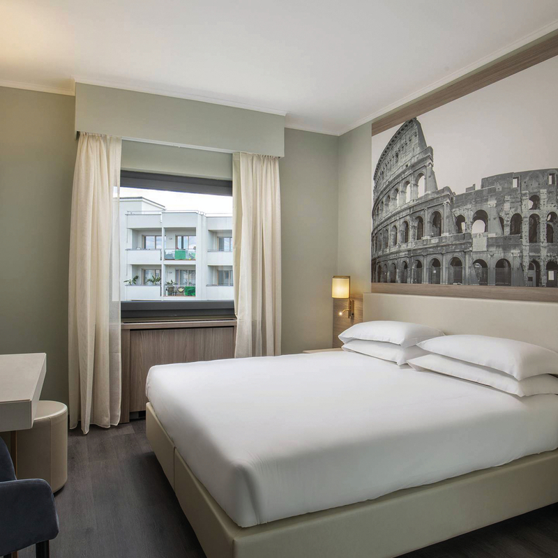 Modernes Hotelzimmer mit Doppelbett und großem Wandbild des Kolosseums.