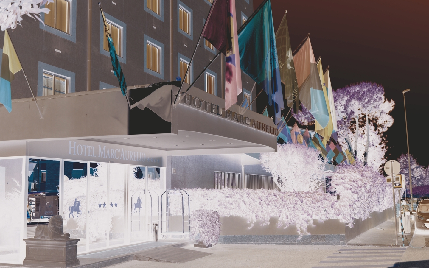 Außenansicht des Hotels Marc Aurelio mit Fahnen am Eingang.