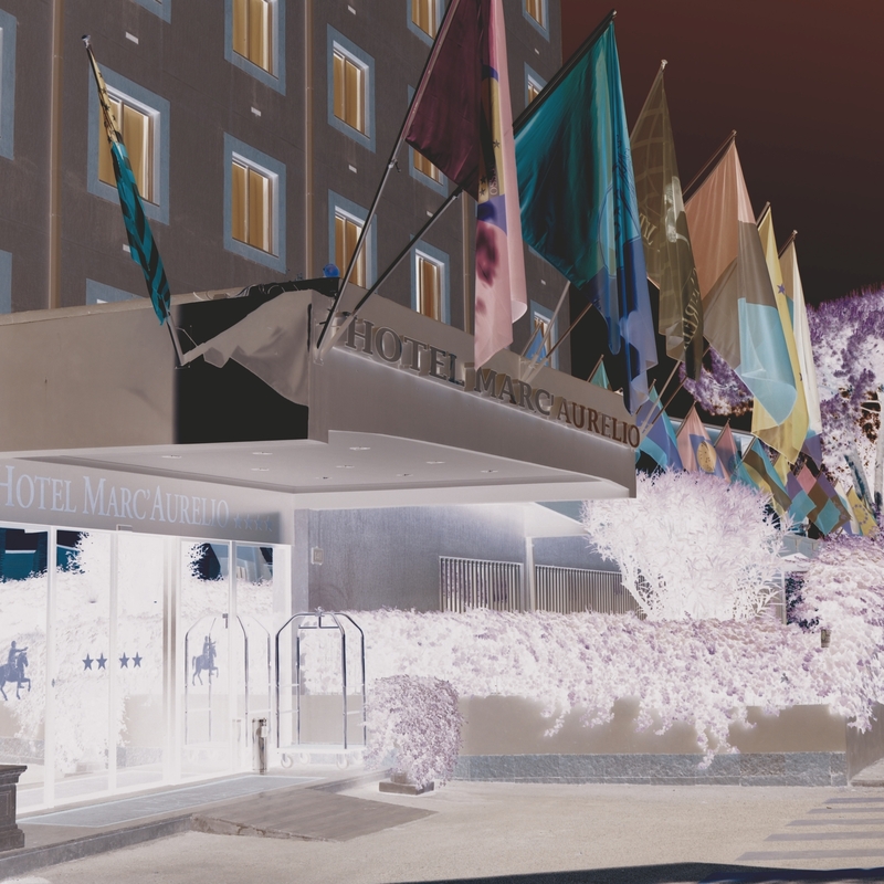 Außenansicht des Hotels Marc Aurelio mit Fahnen am Eingang.