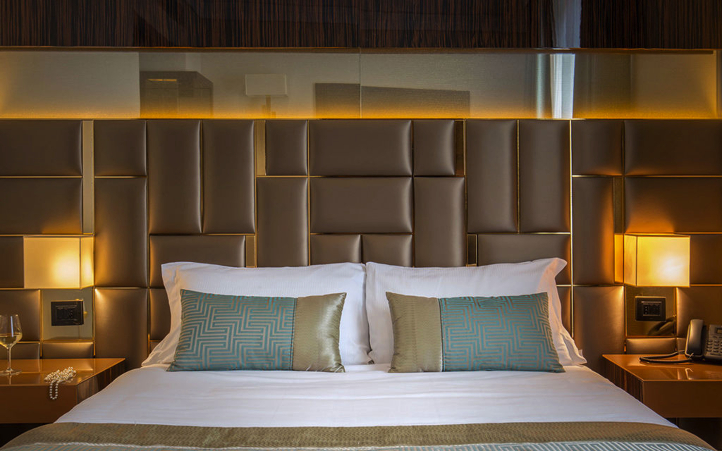 Hotelzimmer mit Doppelbett, dekorativen Kissen und eleganter Beleuchtung.