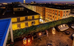 Blick von einer Terrasse bei Nacht auf beleuchtete Gebäude in Rom.