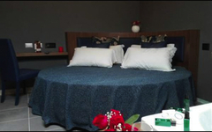 Rundes Hotelbett in modernem Zimmer mit dunklen Wänden und Dekor.