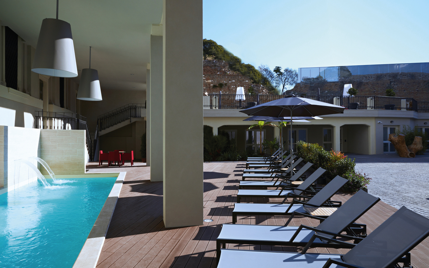 Hotelpoolbereich mit Liegestühlen und Sonnenschirmen in Rom, Italien.