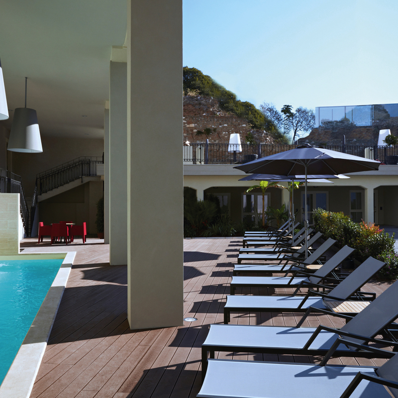 Hotelpoolbereich mit Liegestühlen und Sonnenschirmen in Rom, Italien.